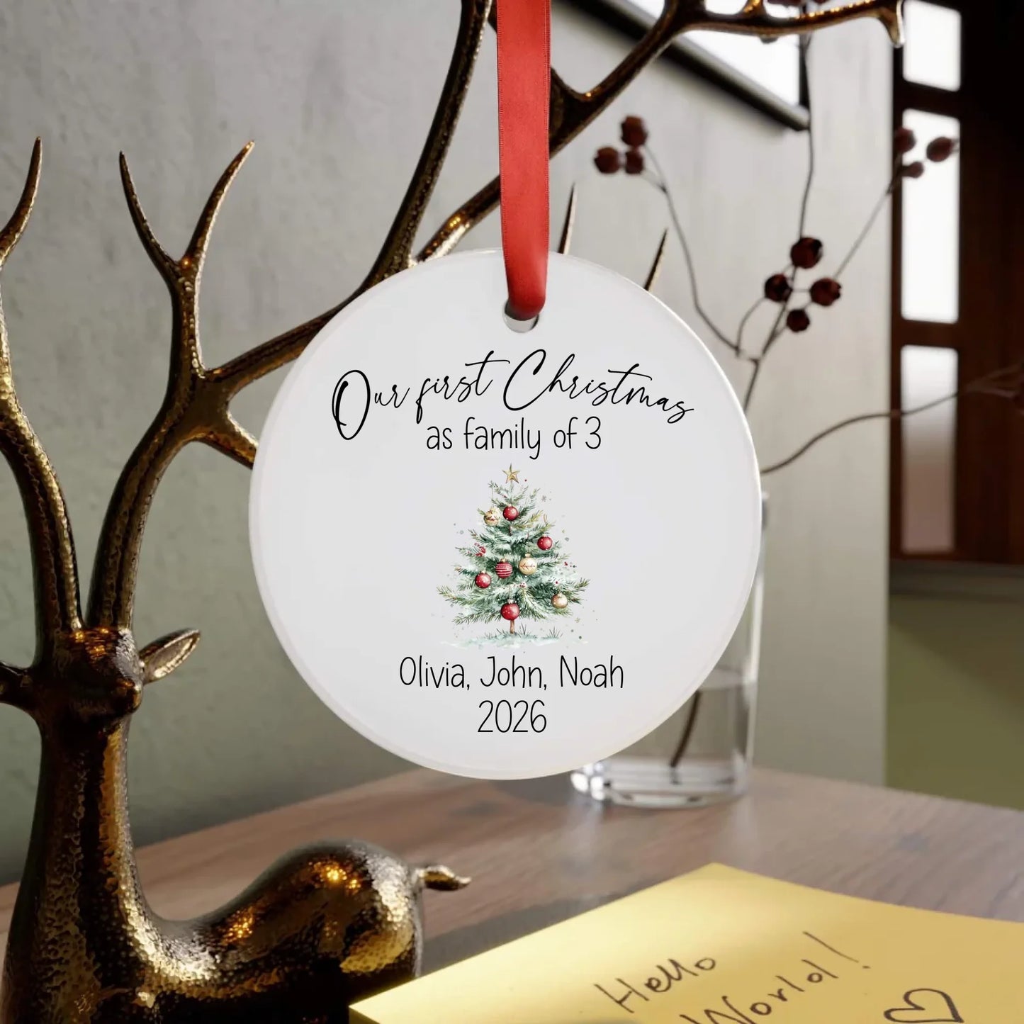 Personalized Christmas ornament with tree design and text, hanging on a branch.