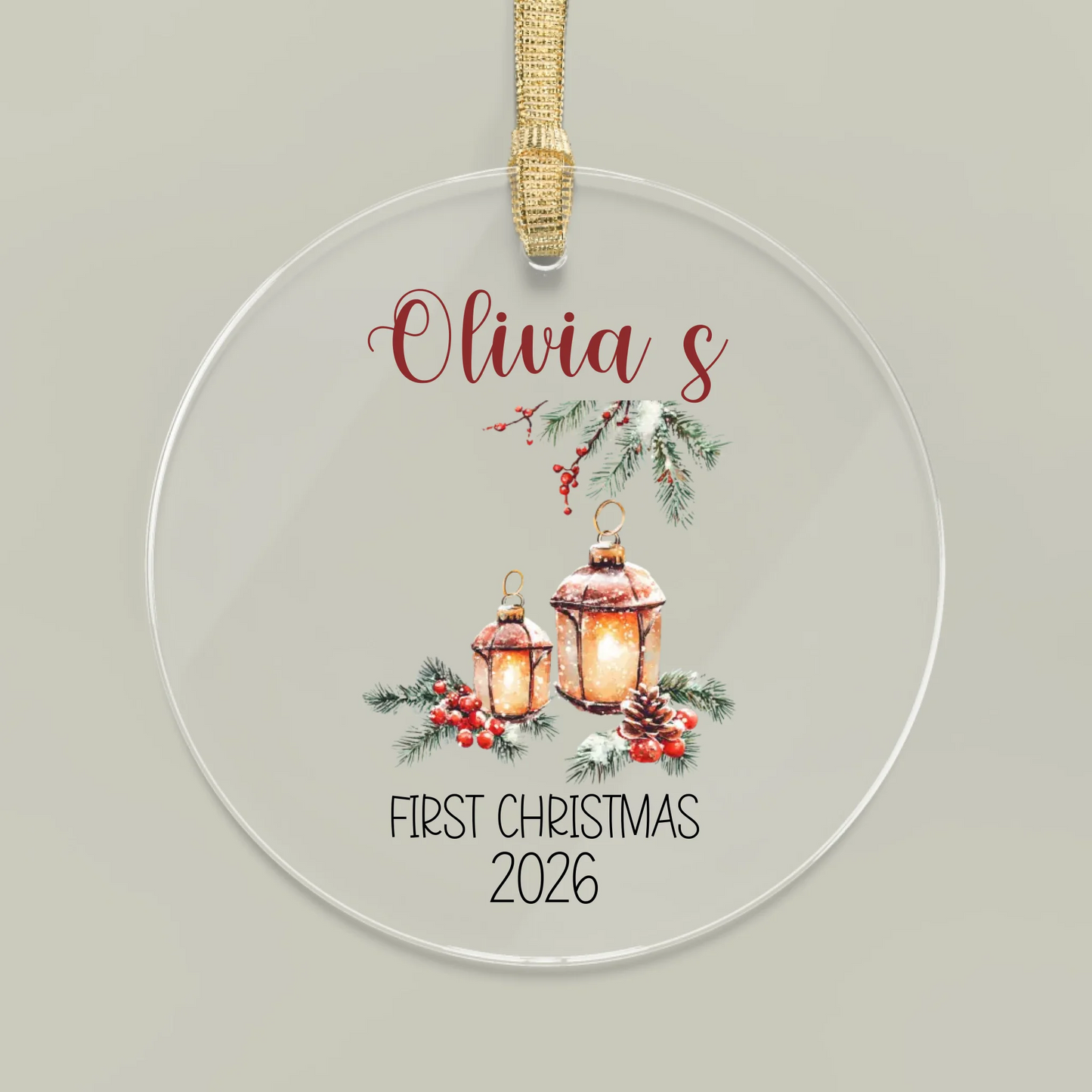 Round Christmas ornament with lanterns and 'Olivia's First Christmas 2026' text on a light gray background.